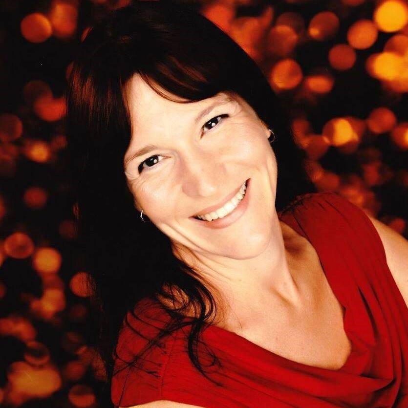 headshot of a smiling caucasian woman with dark brown hair, dark eyes, and a red dress